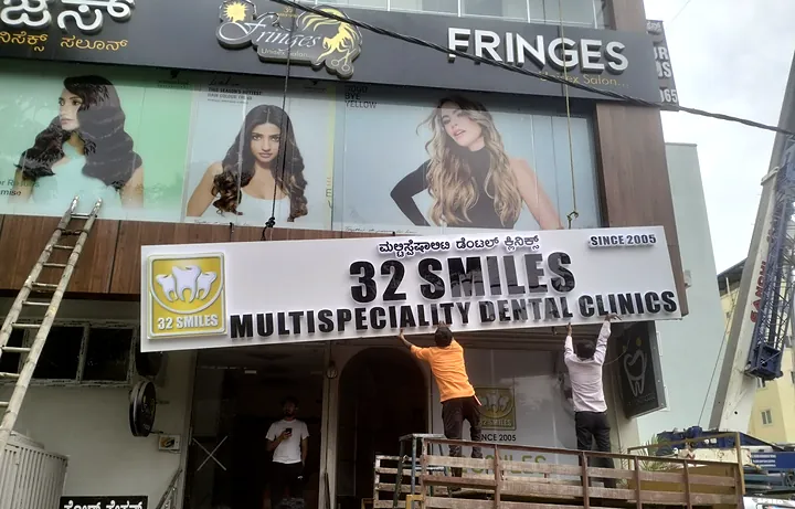 Moeen team installing a 32 Smiles Multispeciality Dental Clinics board