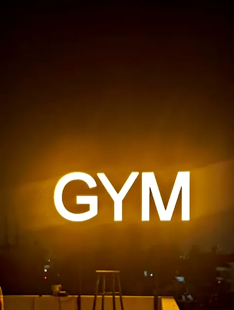 GYM in bright white lit letters against a warm night sky