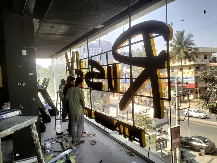 Installer fitting large 3D letters to a glass facade on an upper floor