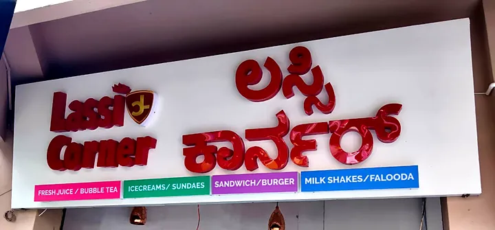 Lassi Corner fascia by day: red 3D letters with category strips