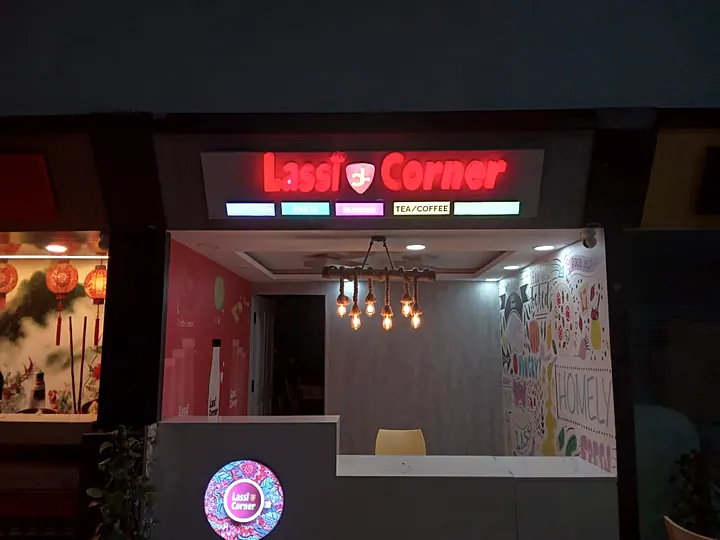 Lassi Corner outlet with lit fascia letters and a glowing round logo on the counter