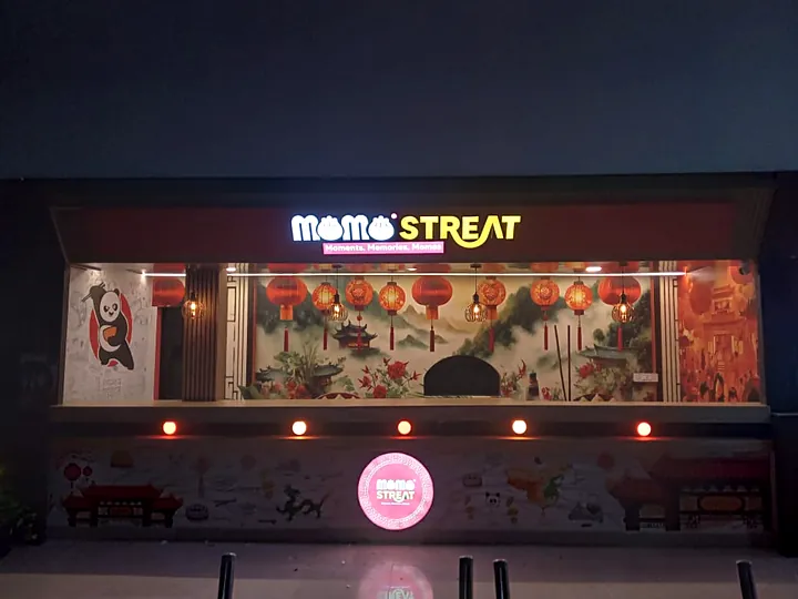 Momo Streat outlet at night with lit fascia and round logo sign