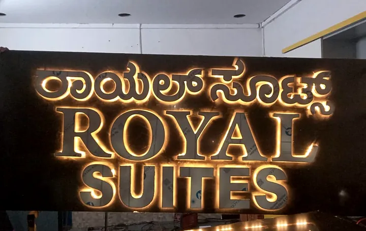 Royal Suites sign with halo-lit gold 3D letters in Kannada and English